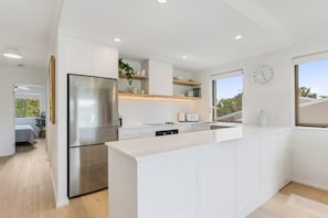 A modern kitchen with white cabinetry, a stainless steel refrigerator, and a built-in island.