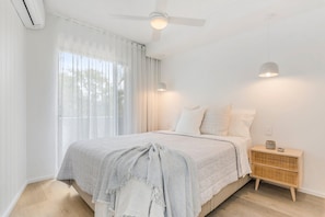 Une chambre à coucher avec un lit, une table de chevet et un ventilateur de plafond.