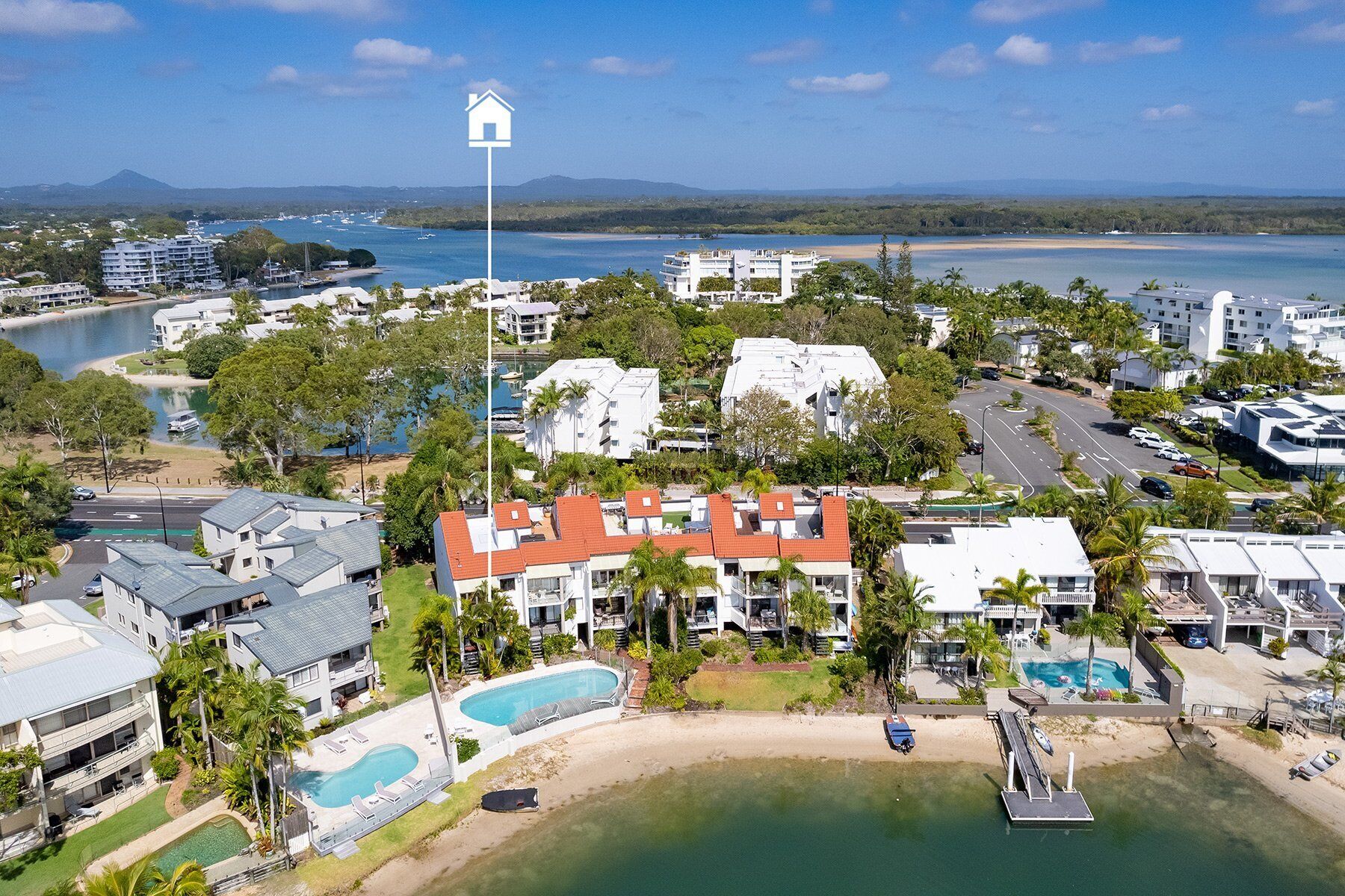 Vista aerea di un resort costiero con diversi edifici, una piscina e una spiaggia.