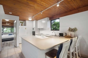 Coffee/tea maker, fridge, stovetop, dining tables