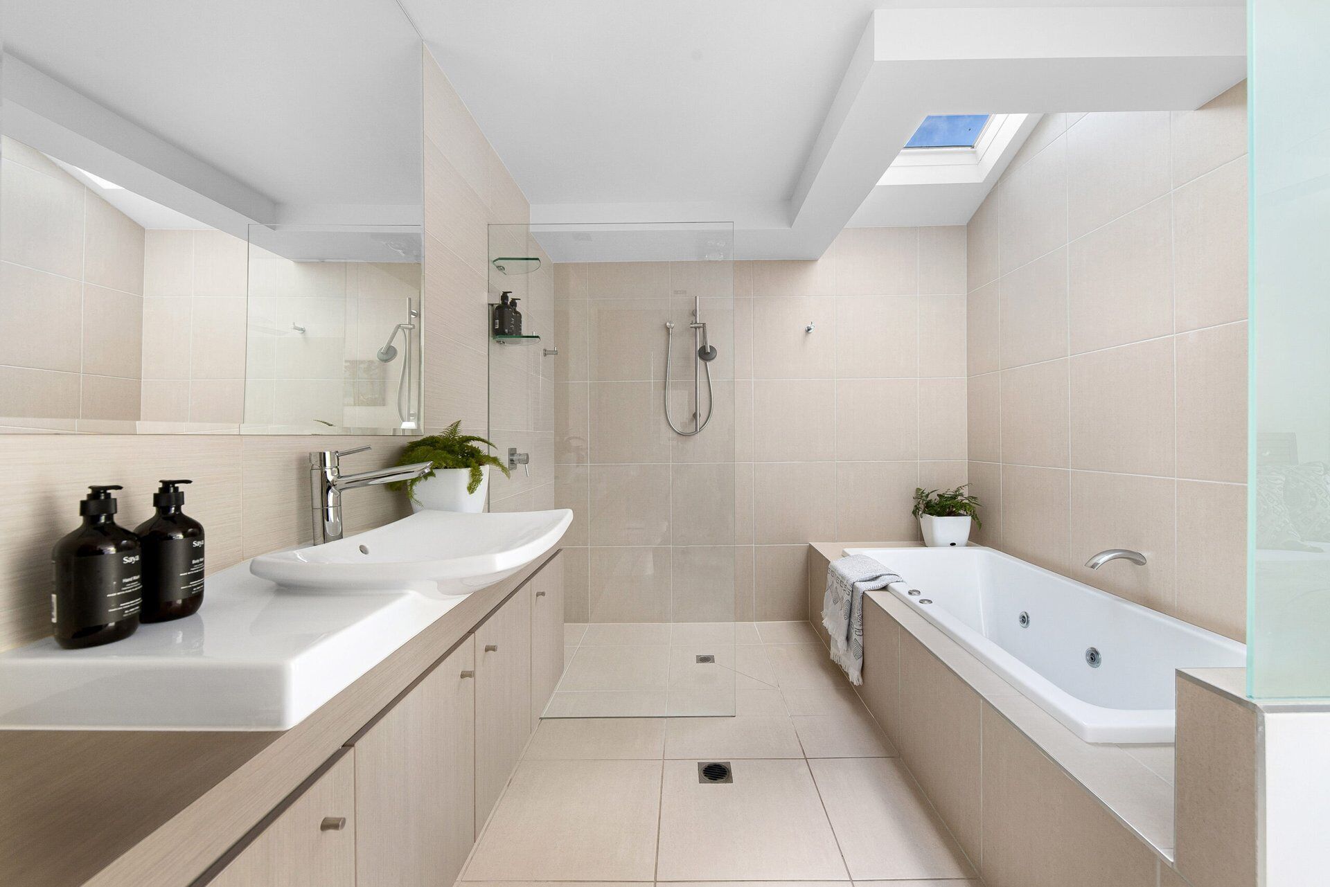 Ein modernes Badezimmer mit Oberlicht, Dusche, Badewanne und zwei Waschbecken.