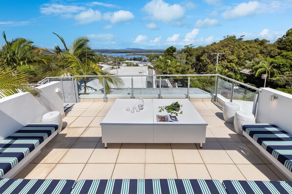 Relax on the rooftop terrace with a scenic view of the coastal landscape and palm trees.