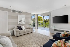 Relax in this stylish living room with a large flat-screen TV, comfortable sofa, and beautiful views of the surrounding greenery.
