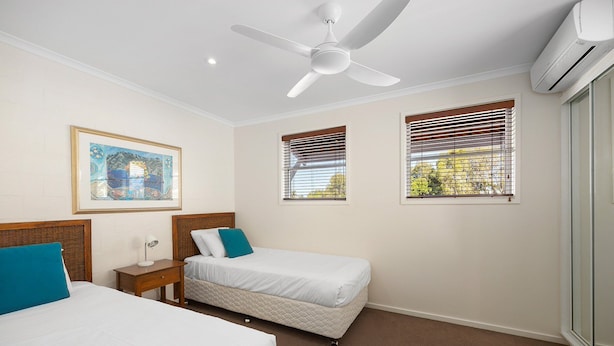 A hotel room with two beds, a ceiling fan, an air conditioning unit, and a framed picture on the wall. - Villa Aqua - Riverside Retreat with Pool (Noosaville)