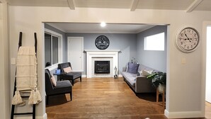 Un salon spacieux avec une cheminée, deux canapés, une table basse et une horloge au mur.
