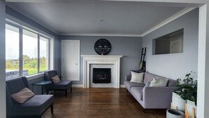 Un salon spacieux doté d’une cheminée, de deux canapés, d’une table basse et d’une grande fenêtre donnant sur l’extérieur.