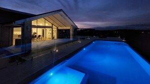 Une maison moderne avec une piscine, au crépuscule.