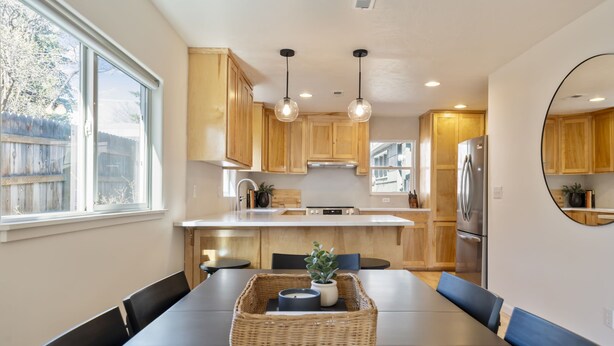A modern kitchen with wooden cabinets, a central island, and pendant lighting. - BEST location in Bend! ~HOT TUB!~ (Bend)