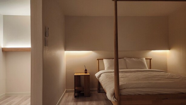 A bedroom with a canopy bed, a bedside table, and a nightstand.