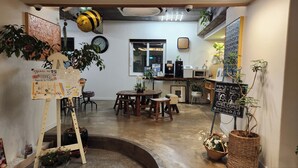A cozy café with wooden furniture, a chalkboard sign, and various plants.