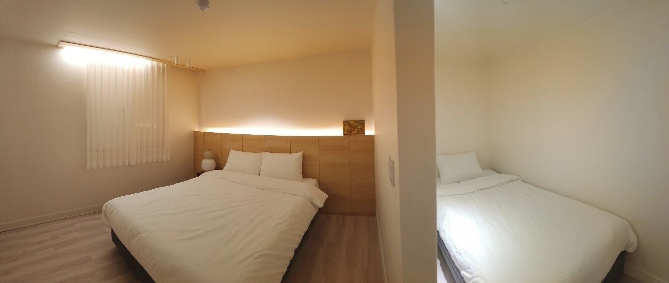 Una habitación de hotel con una cama grande, una mesita de noche y un cabecero con iluminación integrada.
