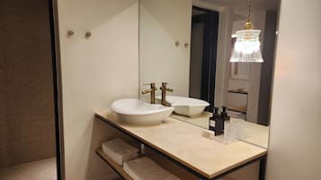 A bathroom with a large mirror, two sinks, a towel rack, and a hanging light fixture.