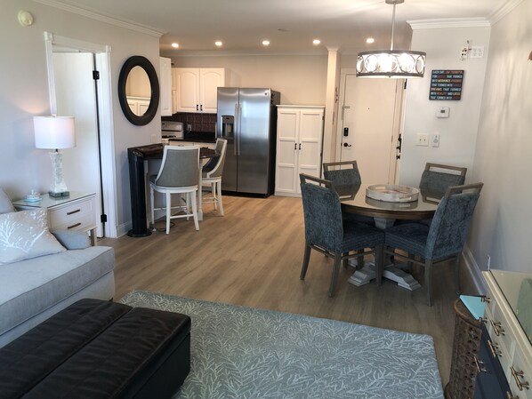 A modern kitchen with white cabinets, a refrigerator, and a dining area with a round table and chairs.