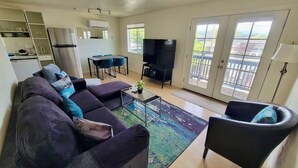A living room with a sofa, armchair, TV, and a dining area with chairs.