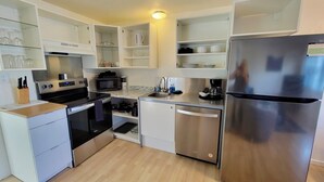 A modern kitchen with stainless steel appliances, white cabinetry, and a wooden countertop.