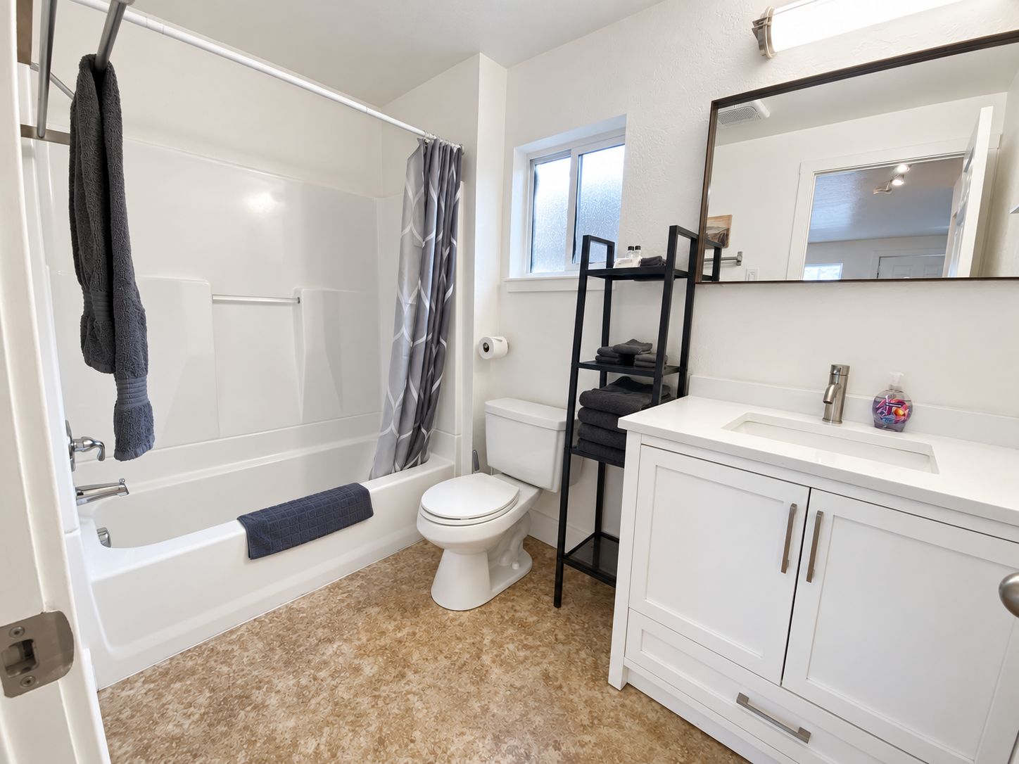 A bathroom with a bathtub, toilet, and a vanity with a mirror.