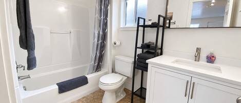 A bathroom with a bathtub, toilet, and a vanity with a mirror.