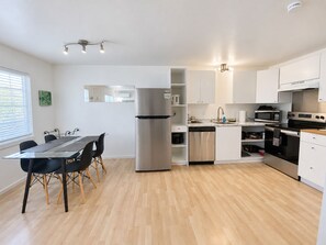 Een moderne keuken met een eethoek, roestvrijstalen apparatuur en een houten vloer.