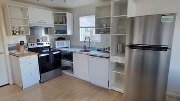 A modern kitchen with stainless steel appliances, white cabinetry, and a wooden countertop.