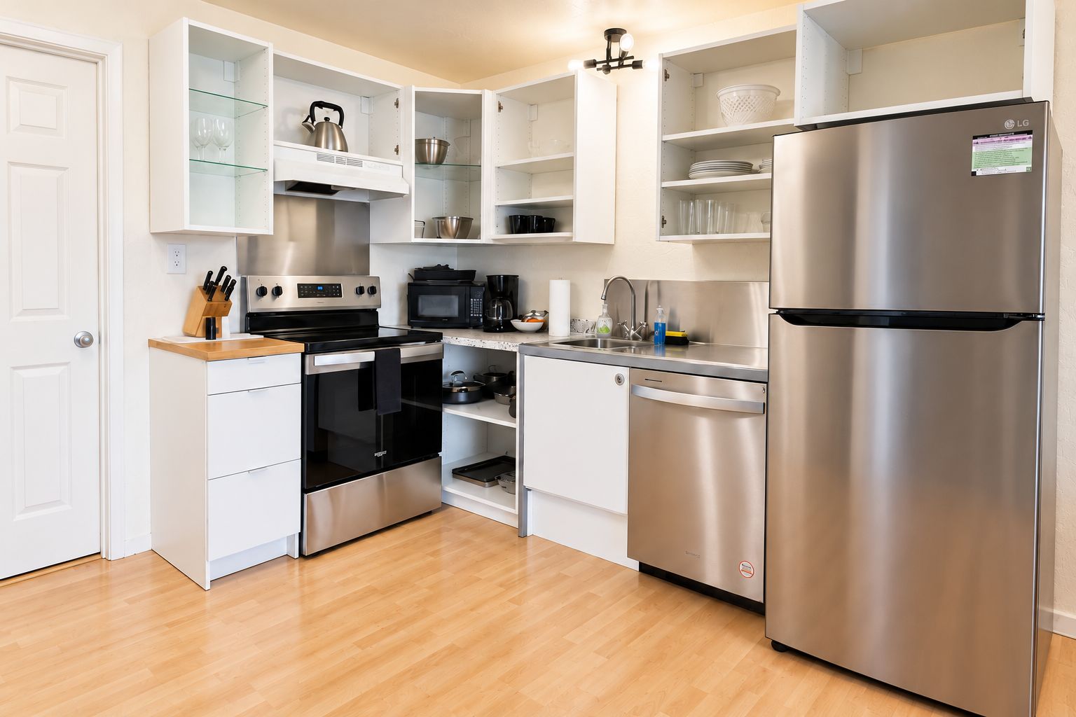 A compact kitchen with a stainless steel refrigerator, a microwave, an oven, and a dishwasher.