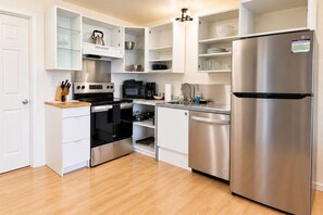 Una cocina compacta con un refrigerador de acero inoxidable, un microondas, un horno y un lavavajillas.