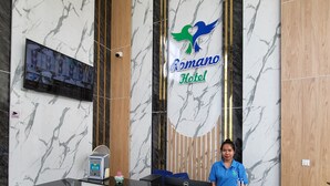 A hotel reception desk with a marble wall, a digital display, and a sign for Romano Hotel. - Romano Hotel (Kampot)