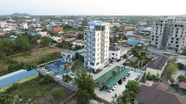 A hotel with a rooftop pool, surrounded by residential buildings and greenery. - Romano Hotel (Kampot)