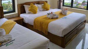 A hotel room with two beds, a large window with a view of a body of water and buildings, and artwork on the wall. - Romano Hotel (Kampot)