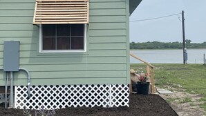 Une maison verte avec une fenêtre, une porte en bois et une clôture blanche.