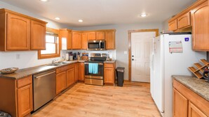 A kitchen with wooden cabinets, stainless steel appliances, and a tiled backsplash. - Welcome to the Middle Fork Cabin of Fairplay (Fairplay)
