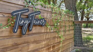 A wooden wall with the name "Tiny Tainer" in stylized lettering.