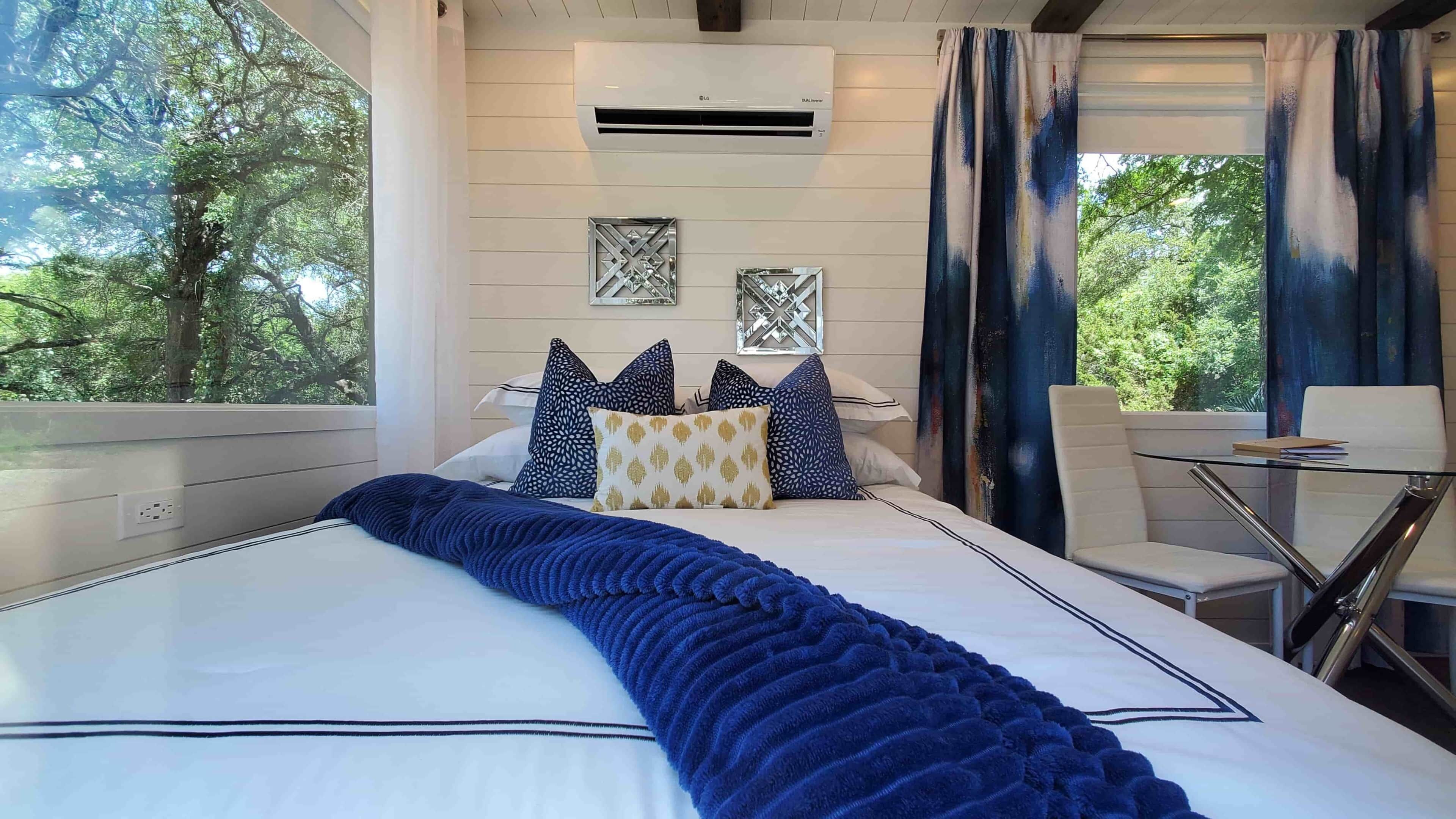 Une chambre à coucher avec un lit, des oreillers, une couverture, une table et des chaises.