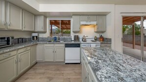 Una cocina moderna con armarios blancos, encimeras de granito y electrodomésticos integrados.