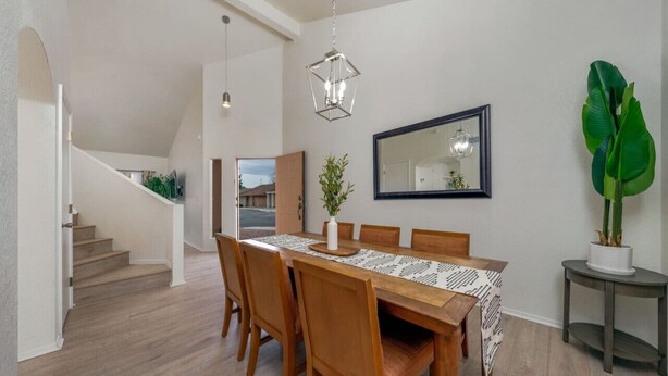 Un comedor con una mesa de madera, sillas y un espejo grande en la pared.