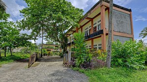 A multi-story building with a central courtyard, surrounded by lush greenery and a gravel path leading to the entrance. - OYO 91877 Mushroom Pondok Ator Syariah Hotel (Pangandaran)
