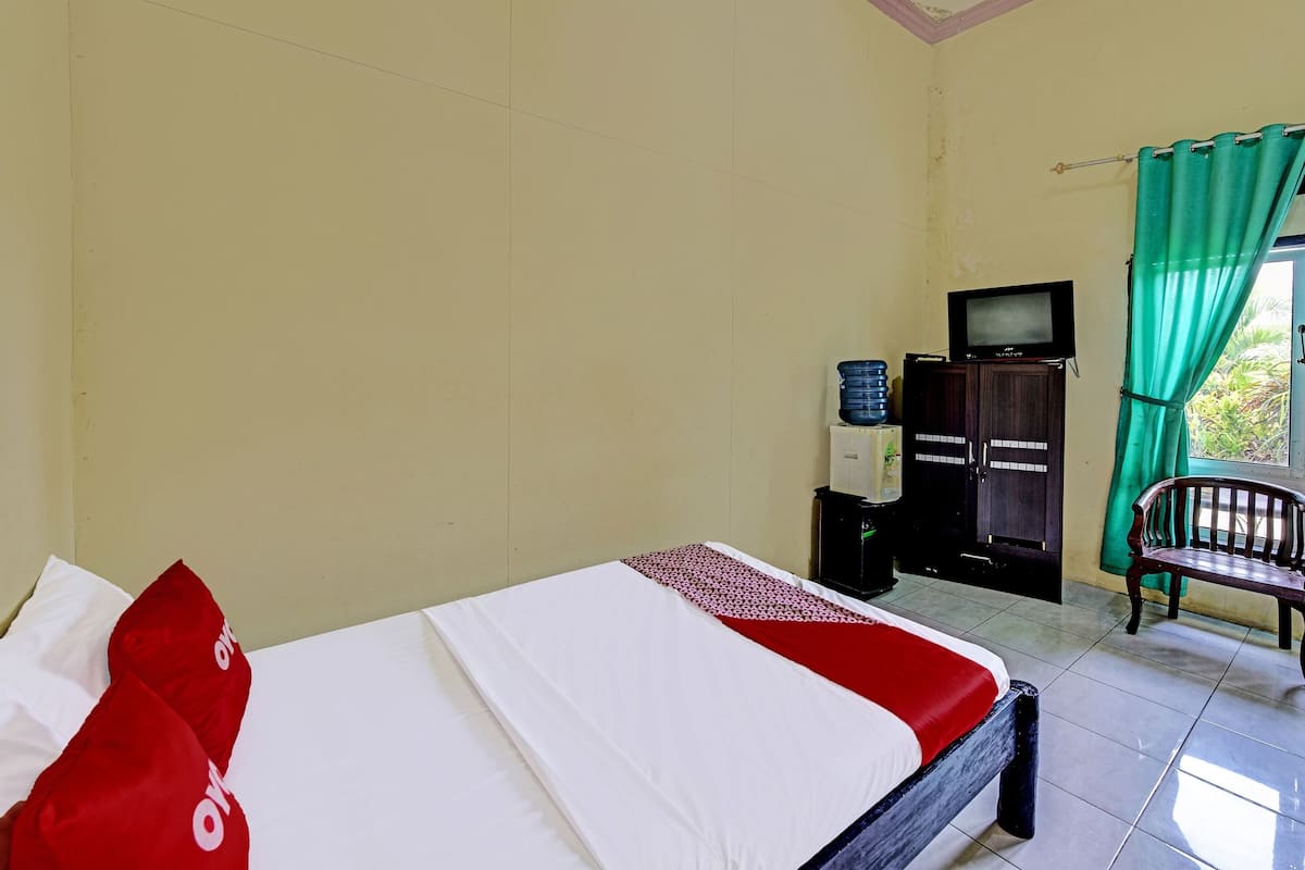 A hotel room with a bed, a television, a water dispenser, and a chair.