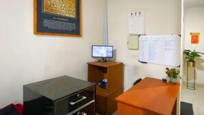 A room with a desk, a computer monitor, a filing cabinet, a framed poster, a whiteboard, and a plant. - OYO 91877 Mushroom Pondok Ator Syariah Hotel (Pangandaran)