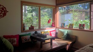 Ein gemütliches Zimmer mit einer Bank, Kissen und einem Fenster mit Kunstwerk.
