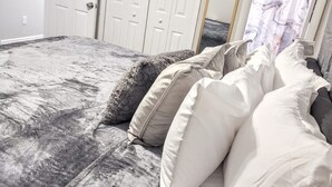 Une chambre à coucher avec un grand lit, des murs blancs et une porte blanche.