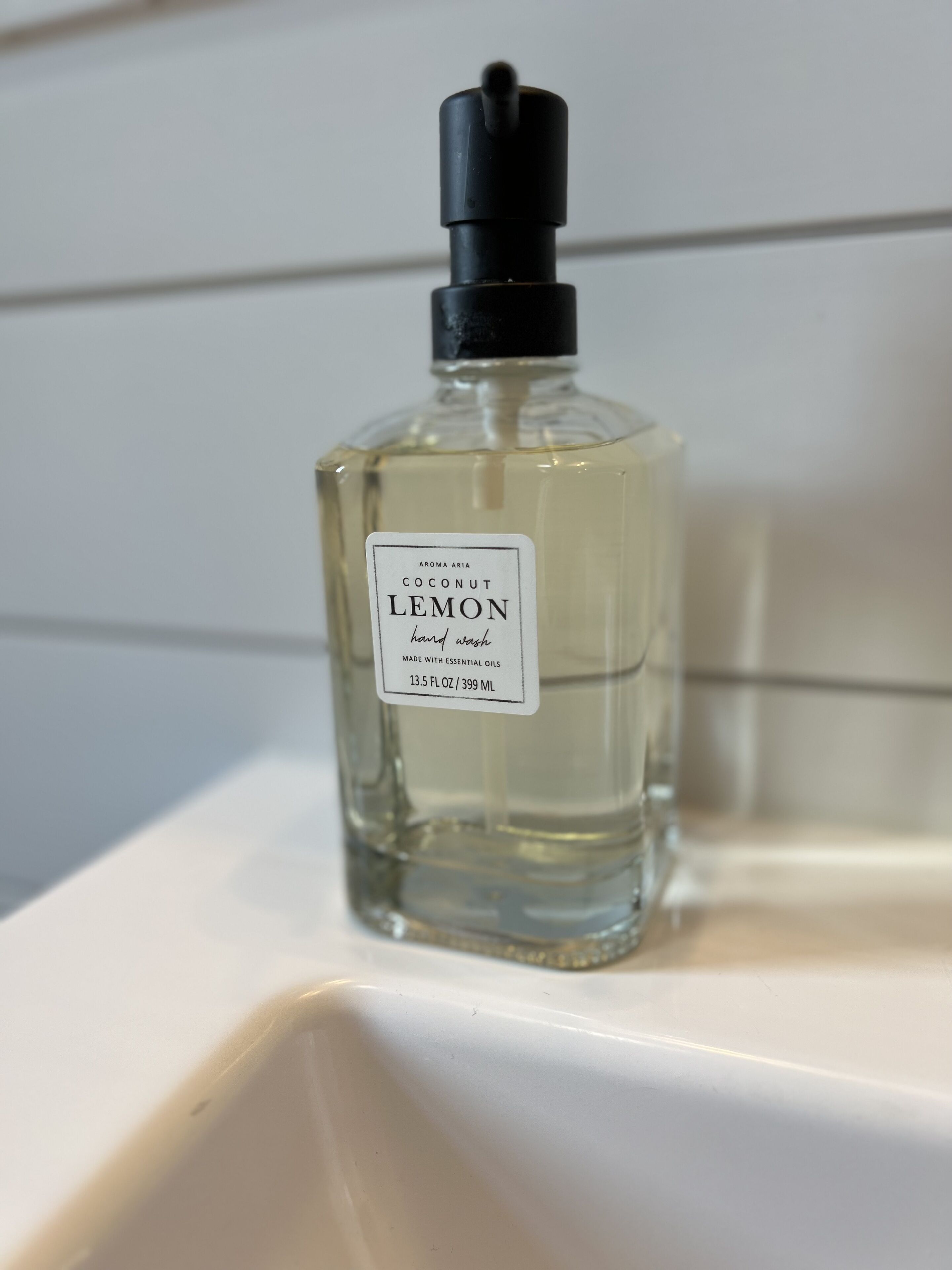 A bottle of coconut lemon hand wash on a white surface.
