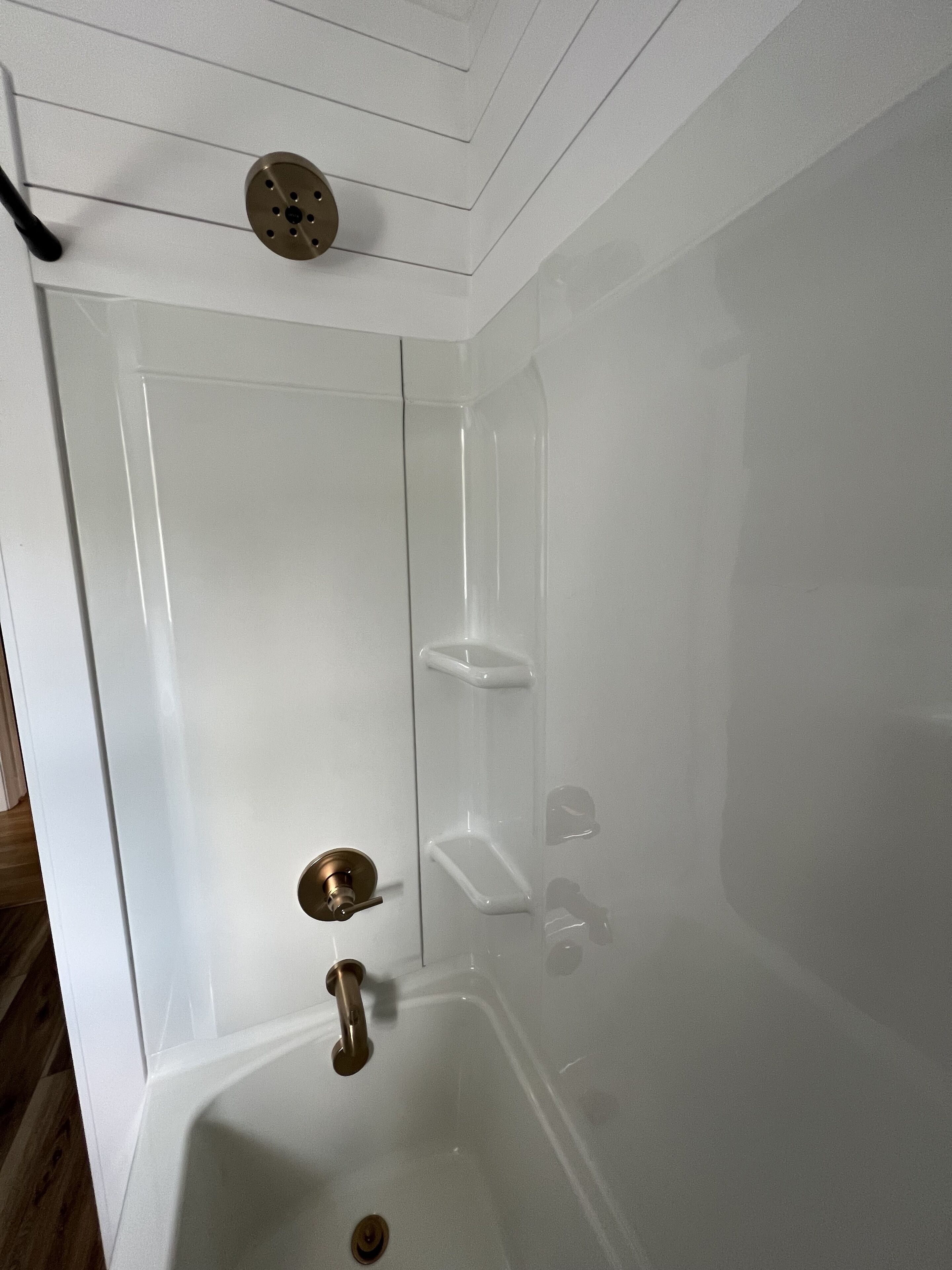 A modern bathroom with a bathtub, a shower, and a toilet. There are three shelves for toiletries.
