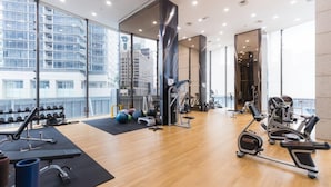 Een moderne sportschool met diverse fitnessapparaten, grote ramen en uitzicht op een stadsgezicht.