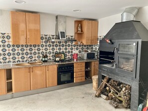 Eine Küche mit Holzschränken, einer Mikrowelle, einem Herd und einem Holzofen.