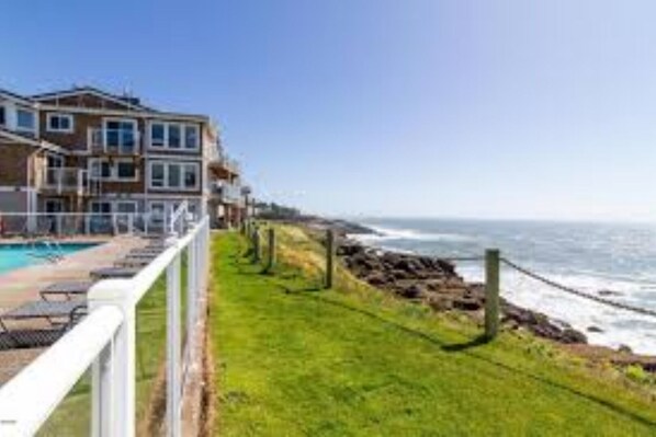Overlooking the ocean, this property offers a balcony with a view of the adjacent grassy area.
