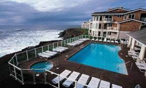 Relax by the resort's large rectangular pool, featuring a smaller circular section, surrounded by lounge chairs.