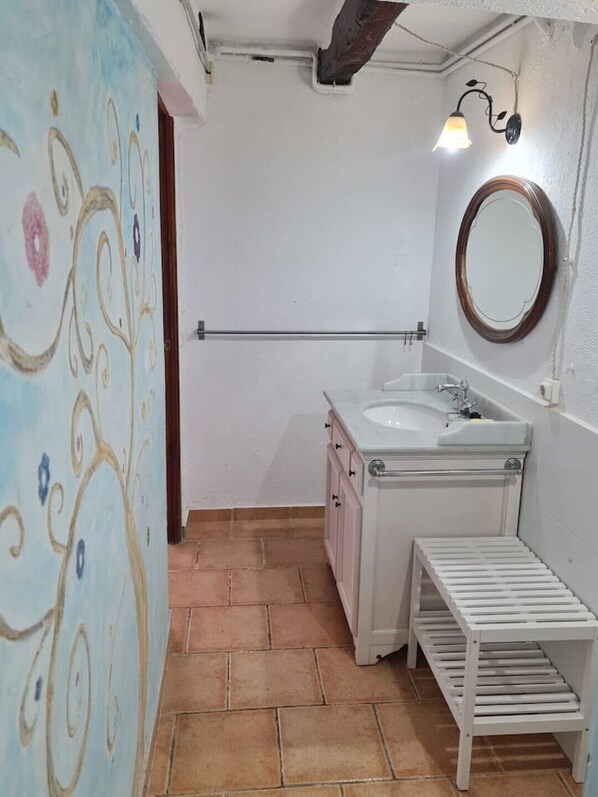 Bathroom features a white sink, mirror, and terracotta tile flooring.