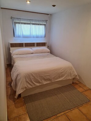 Cozy retreat with a single bed, plain bedspread, and patterned window treatment.