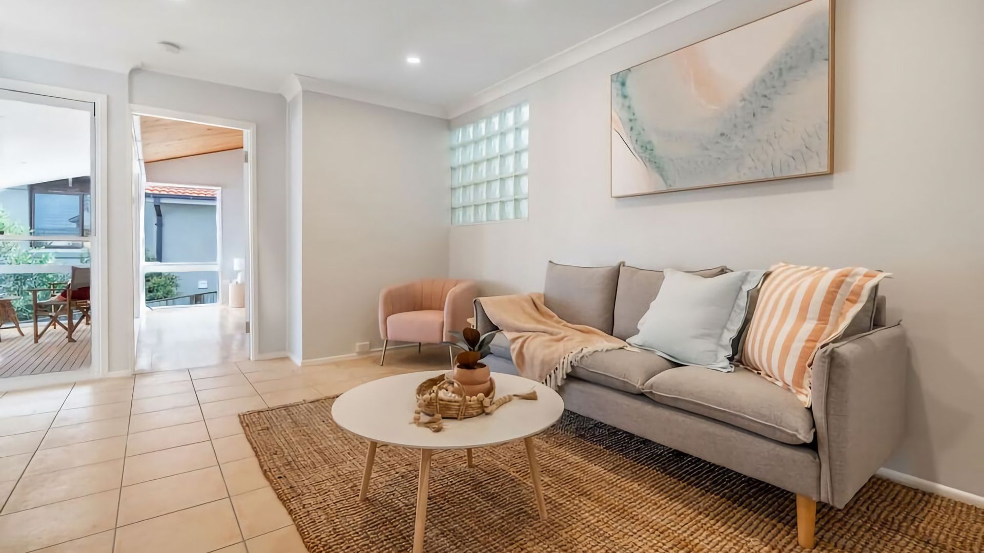 A modern living room with a grey sofa, a round coffee table, and a large abstract painting on the wall.
