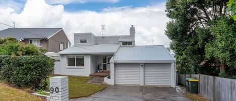 A residential house with a garage, a front porch, and a well-maintained lawn.