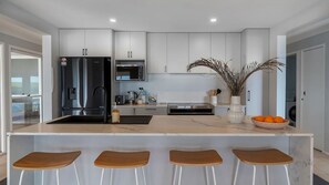 Eine moderne Küche mit einer zentralen Kochinsel, Barhocker und einem Kühlschrank.